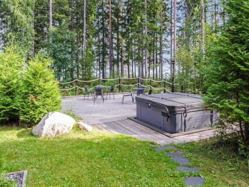 a wooden deck with tables and chairs in a forest at Holiday Home Villa usva by Interhome in Kolinkylä