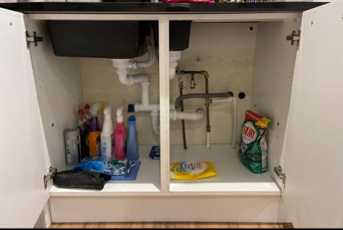 a bathroom cabinet with a sink and cleaning supplies at Central Cheltenham Apartment in Cheltenham