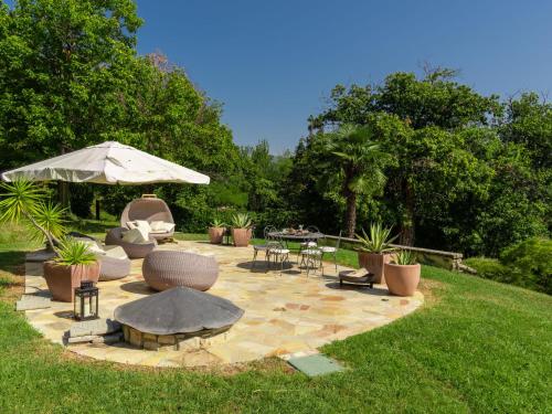 um pátio com mesas e cadeiras e um guarda-sol em Villa Tenuta La Maronera by Interhome em Colombaro