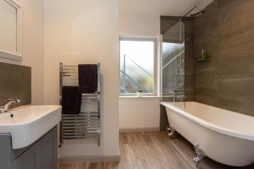 baño con bañera, lavabo y ventana en Howgills House Hotel, en Sedbergh