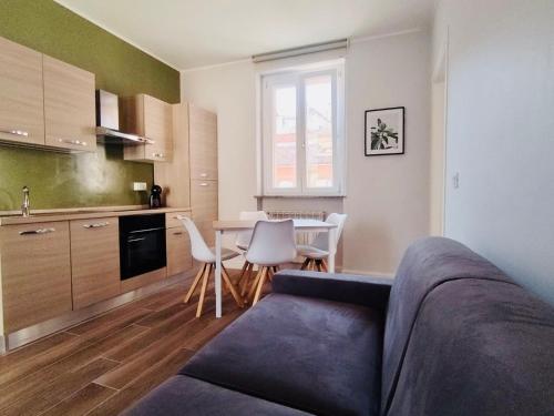 ein Wohnzimmer mit einem Sofa und eine Küche mit einem Tisch in der Unterkunft HH Hermoso Housing Asti in Asti