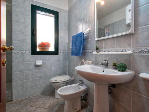 a bathroom with a sink and a toilet and a mirror at Apartment L'Oasi Trilo A2 by Interhome in Trinità dʼAgultu