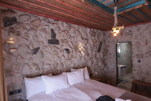 a bedroom with a stone wall with a bed at Stone Owl Otel & Restaurant in Uchisar