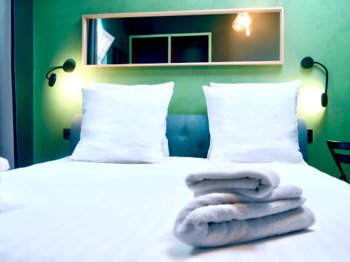 uma cama branca com uma pilha de toalhas em L'Emeraude - Paris 19ème Arrondissement em Paris