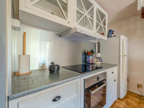  La cuisine est équipée de placards blancs et d'un réfrigérateur. dans l'établissement Apartment Les Bastides de Grand Stade-12 by Interhome, à Saint Cyprien Plage