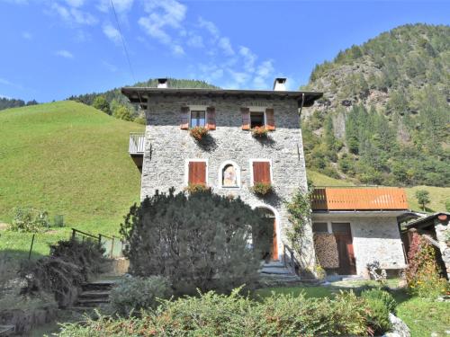 a stone house on a hill with flowers on it at Apartment La Casetta di Biorca by Interhome in Tartano