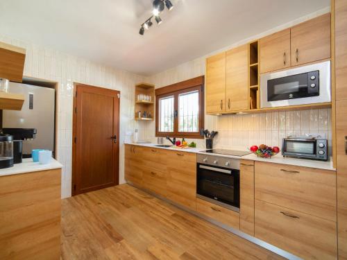 cocina grande con armarios de madera y microondas en Villa Agave by Interhome, en Calpe