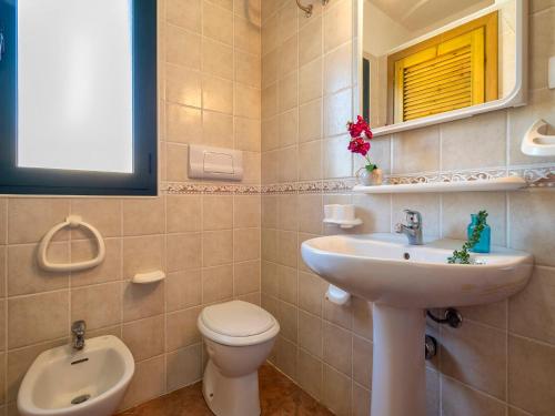 a bathroom with a sink and a toilet and a mirror at Apartment L'Oasi Trilo A7 by Interhome in Trinità dʼAgultu