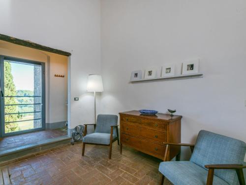 a living room with two chairs and a dresser and a window at Apartment Casa dei Granai by Interhome in Lorenzana
