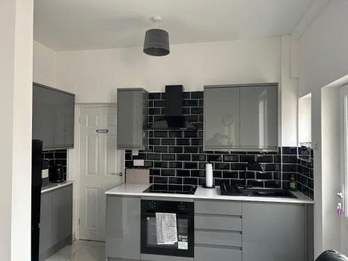 a kitchen with a black and white tile wall at Modern 1 bed Flat with Private Courtyard in Newport