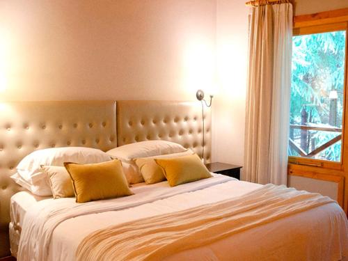 a bedroom with a large bed with yellow pillows at ONA Apart Hotel and Spa in Villa La Angostura