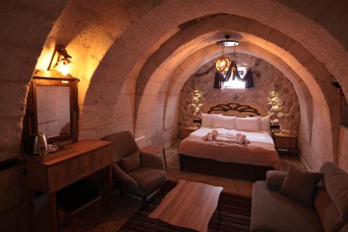 a bedroom with a bed and a chair in a room at Stone Owl Otel & Restaurant in Uchisar