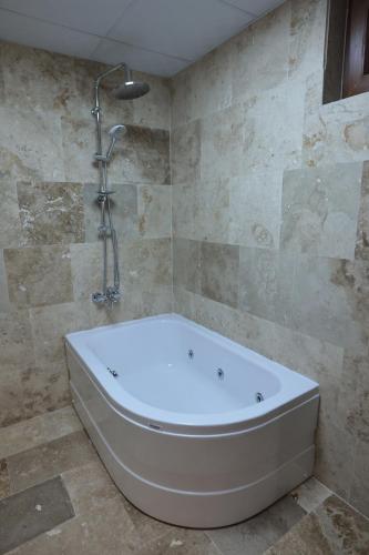 a bath tub in a bathroom with a shower at Stone Owl Otel & Restaurant in Uchisar