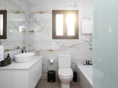 a white bathroom with a toilet and a sink at Cocoon Ocean Villa Luxury Escape in Peyia