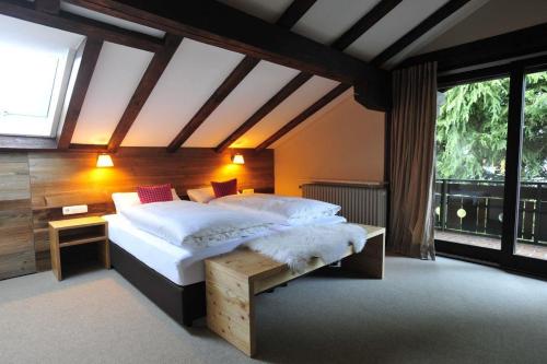 a bedroom with a large bed and a large window at Auszeit in Obermaiselstein