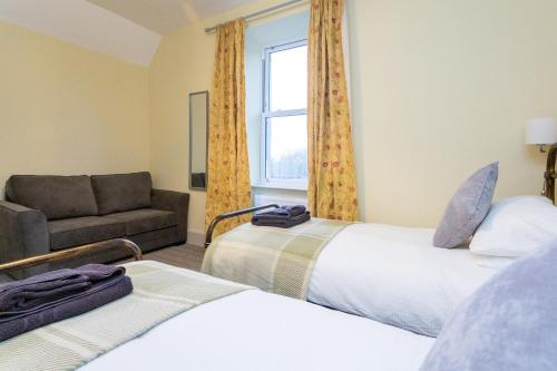 a room with two beds and a couch and a window at Howgills House Hotel in Sedbergh