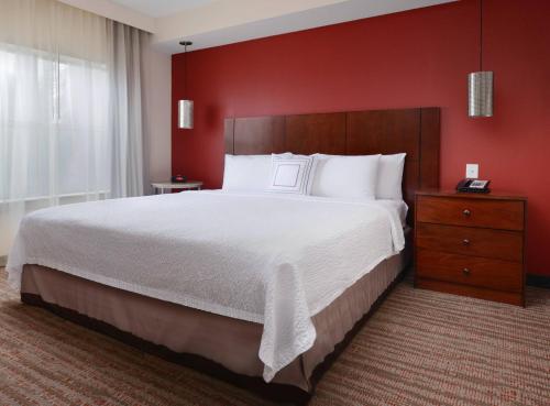 a bedroom with a large bed and a red wall at Residence Inn by Marriott Dallas Plano The Colony in The Colony