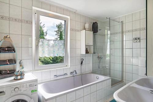 uma casa de banho com uma banheira, um lavatório e uma janela em Ferienwohnung Goldstadtblick em Pforzheim