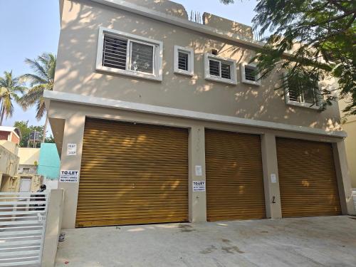 a house with two garage doors in front of it at Downtown Service Apartments in Mysore