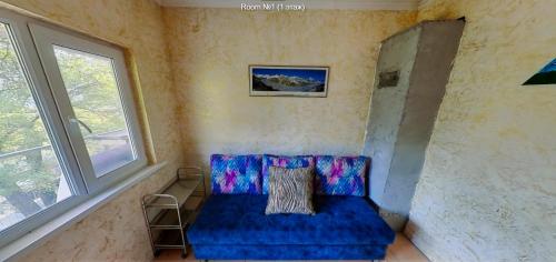 Sofá azul en una habitación con 2 ventanas en Горный дом Monplaisir, en Kamenskoye Plato