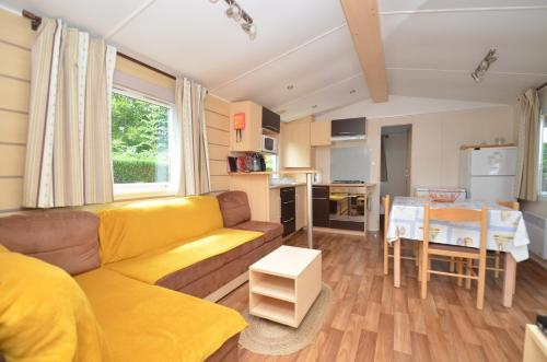 a living room with a yellow couch and a table at Village Vacances 4 etoiles LES MATHES AUX CHARMETTES in Les Mathes