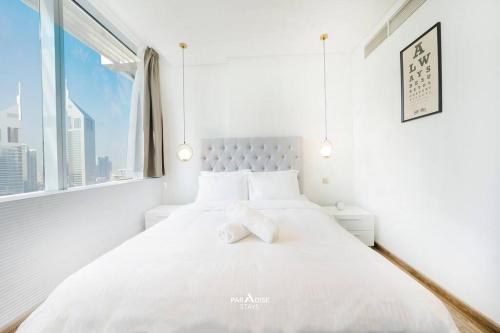 a white bedroom with a large white bed with a window at Sky Gardens DIFC - Sea & City Views in Dubai