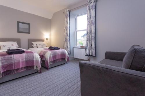 a bedroom with two beds and a couch and a window at Howgills House Hotel in Sedbergh