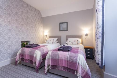 a bedroom with two beds with pink and white blankets at Howgills House Hotel in Sedbergh