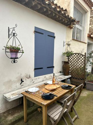 une table en bois avec des chaises et une porte bleue dans l'établissement la maison des lauriers rouges, à Peyriac-de-Mer