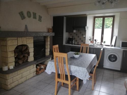 een keuken met een tafel en een open haard bij LE GITE DE LA MAISON ROUGE in Anctoville