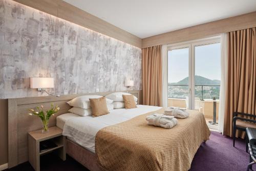a hotel room with a bed and a large window at Hotel Adria in Dubrovnik