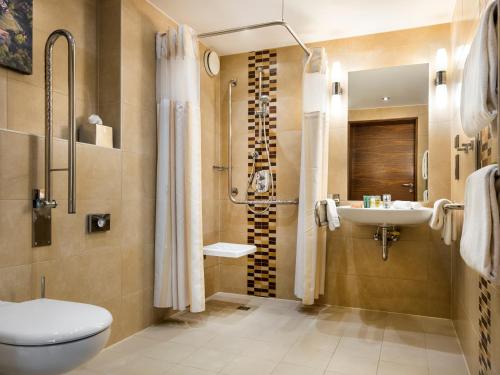 a bathroom with a shower toilet and a sink at Hilton Garden Inn Krakow in Kraków