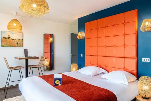 a bedroom with a large bed with an orange headboard at Le Green des Impressionnistes in Ennery