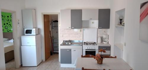 kuchnia z białymi szafkami i stołem z tabelą sidx sidx w obiekcie Apartment in Medulin with sea view, balcony, air conditioning, W-LAN (112-5) w Medulinie