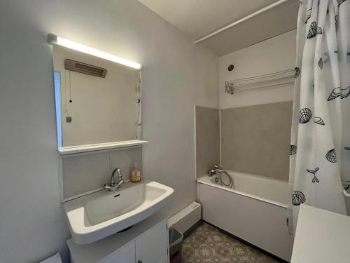 une salle de bain avec un lavabo, une baignoire et un miroir dans l'établissement Appartement T2 face aux pistes avec terrasse, 9 couchages, proche commerces et piscine - FR-1-165A-103, à Enchastrayes
