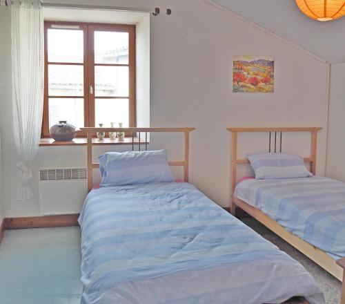 Duas camas num quarto com uma janela em Gencay La maison blanche em Gençay