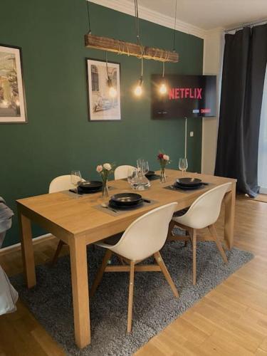 einen hölzernen Esstisch mit weißen Stühlen und einem Tisch in der Unterkunft Zentral * Stilvoll * Nahe HBF * Netflix in Aachen