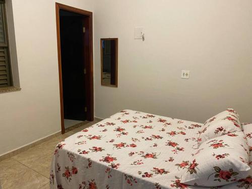 Una cama con una manta blanca con flores rojas. en Casa em Jaú capital do calçado feminino Unoeste e Hospital Amaral Carvalho, en Jaú