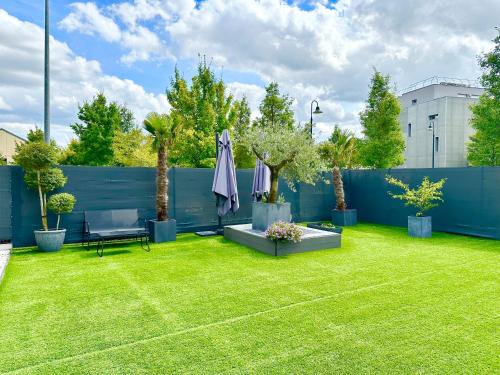 a backyard with a blue fence and a green lawn at Stylish Apartment Disneyland Paris in Chessy