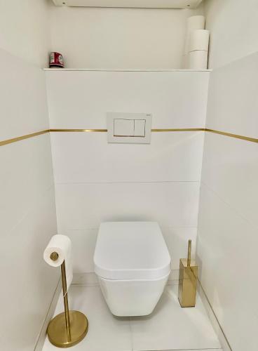 une salle de bains blanche avec des toilettes et un porte-papier toilette. dans l'établissement Stylish Apartment Disneyland Paris, à Chessy