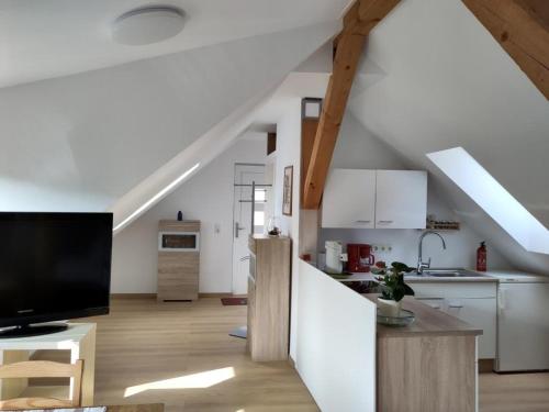 a kitchen and living room with white cabinets and a tv at Ferienwohnung Lärchennest 