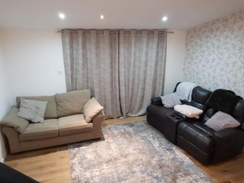 a living room with a black leather couch and a rug at Spacious self-contained annexe in Horbury in Horbury