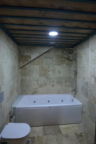 a white bath tub in a bathroom with a toilet at Stone Owl Otel & Restaurant in Uchisar