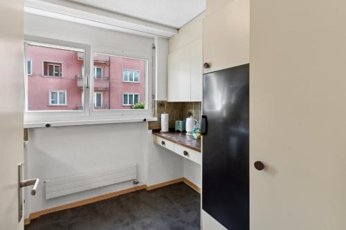 a kitchen with a black refrigerator and a window at Beautiful Boutique Apartment DRAHTZUG8 in Zürich
