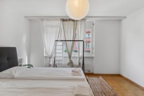 a white bedroom with a bed and a window at Beautiful Boutique Apartment DRAHTZUG8 in Zürich