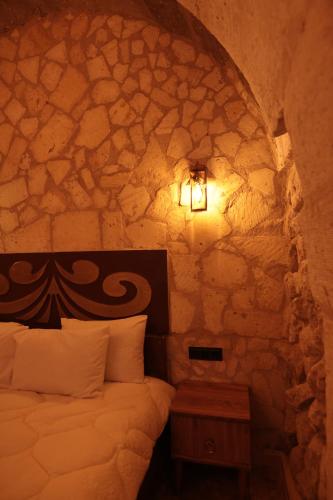 a bedroom with a bed and a stone wall at Stone Owl Otel & Restaurant in Uchisar
