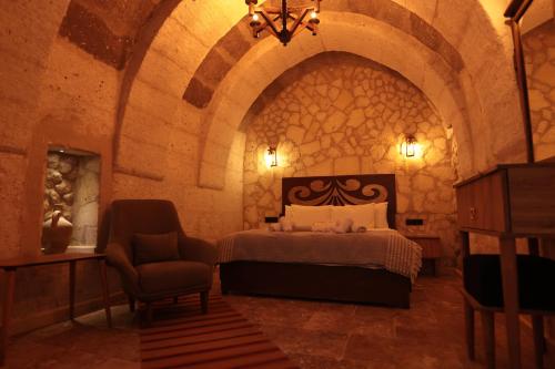 a bedroom with a bed and a chair in a room at Stone Owl Otel & Restaurant in Uchisar