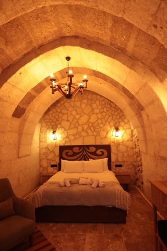 a bedroom with a large bed in a stone wall at Stone Owl Otel & Restaurant in Uchisar