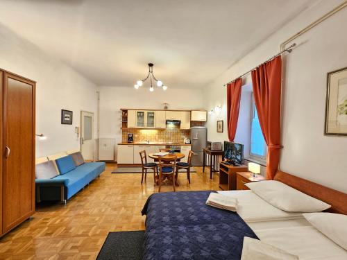 a living room with a blue bed and a kitchen at Spacious central studio Nika 2 Tour As Ljubljana in Ljubljana