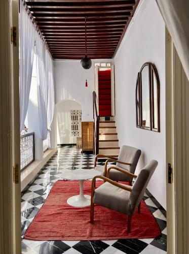 a living room with a table and chairs and a red rug at Riad Tizwa Marrakech in Marrakech